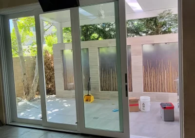View through glass doors to a patio with cleaning supplies and decorative frosted glass panels.